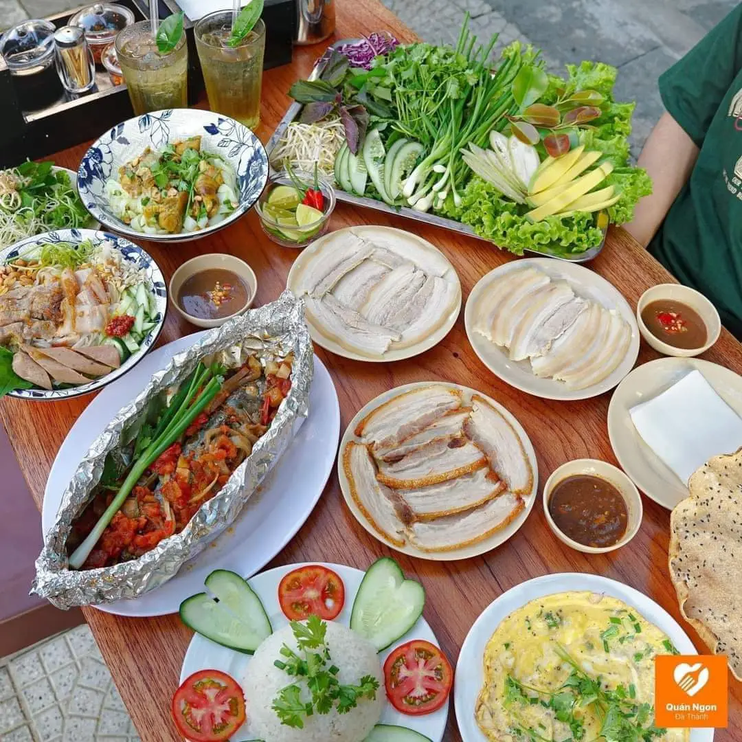 Table at Dai Loc Nang Tho 3 with a plate of boiled pork, roast pork, fish steamed in foil, herbs and a bowl of mam