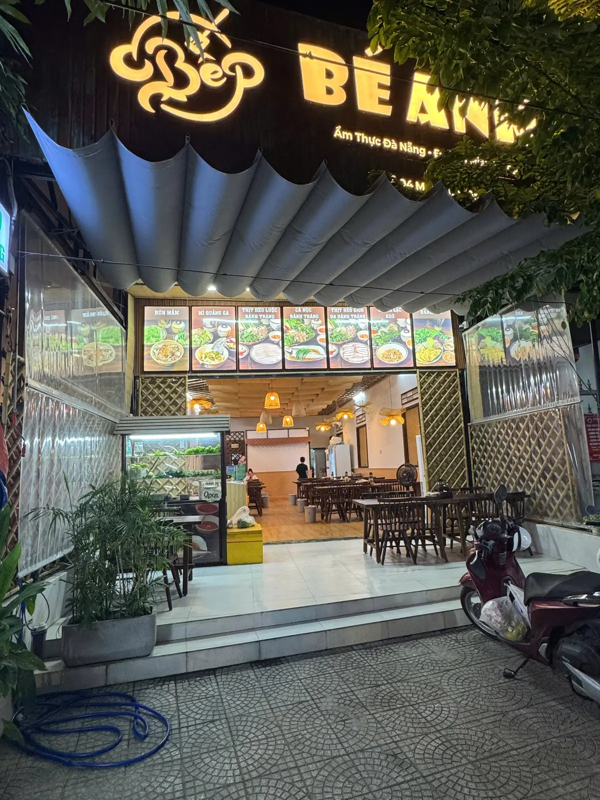 Shopfront of Bep Be Anh with a row of menu boards above and a bright dining room inside
