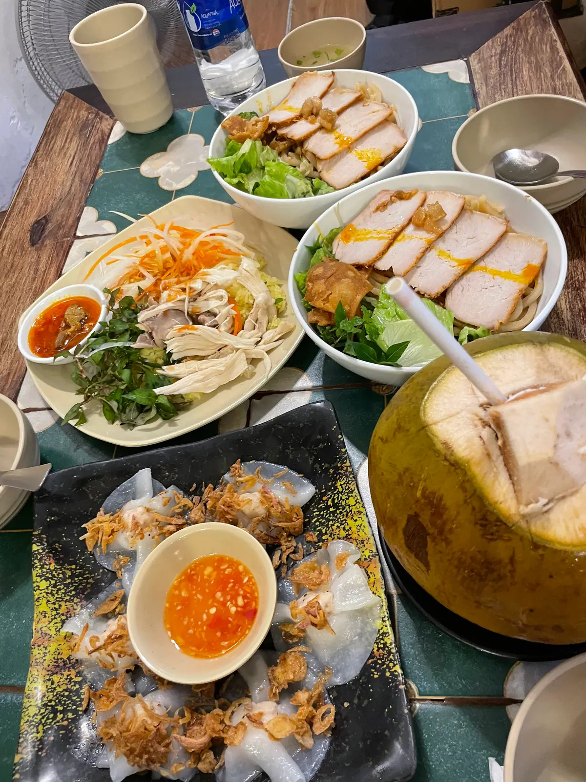 Hai đĩa cao lầu thịt heo cạnh trái dừa và đĩa món ăn kèm trên bàn quán Bá Lễ.