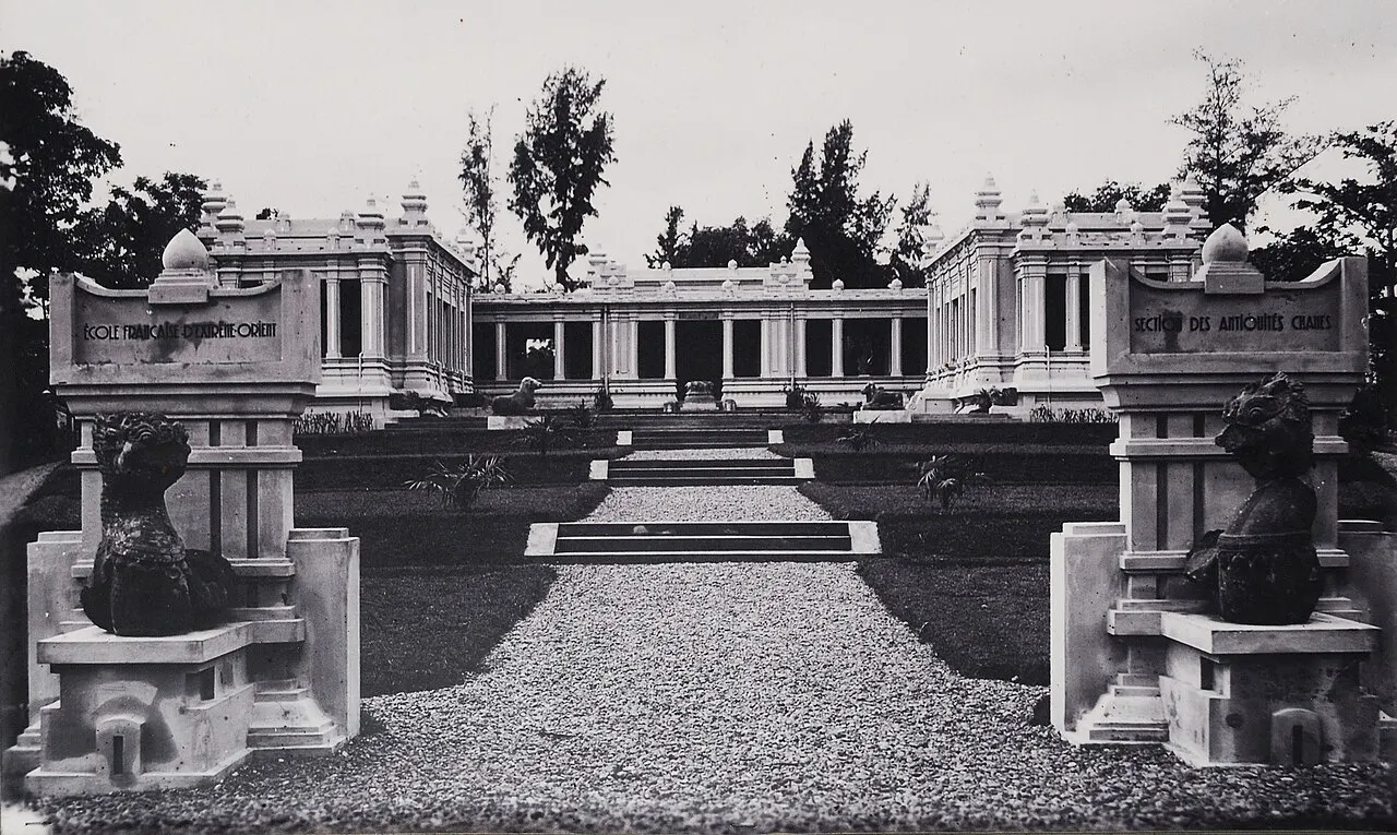 Ảnh đen trắng sân bảo tàng: con đường sỏi giữa hai cột biển ghi École Française d'Extrême-Orient và Section des Antiquités Chames, phía sau là các dãy nhà.