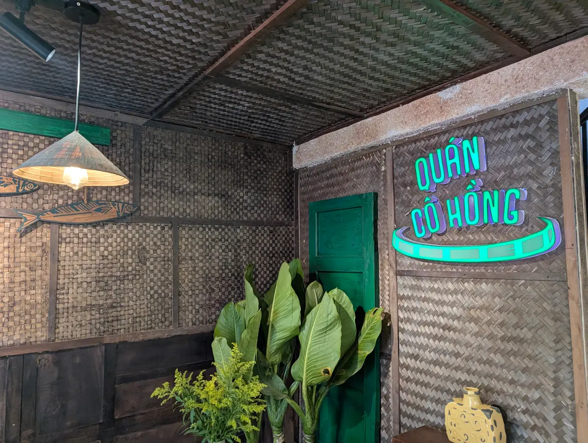 Bảng hiệu neon Quán Cô Hồng trên vách tre trong quán.