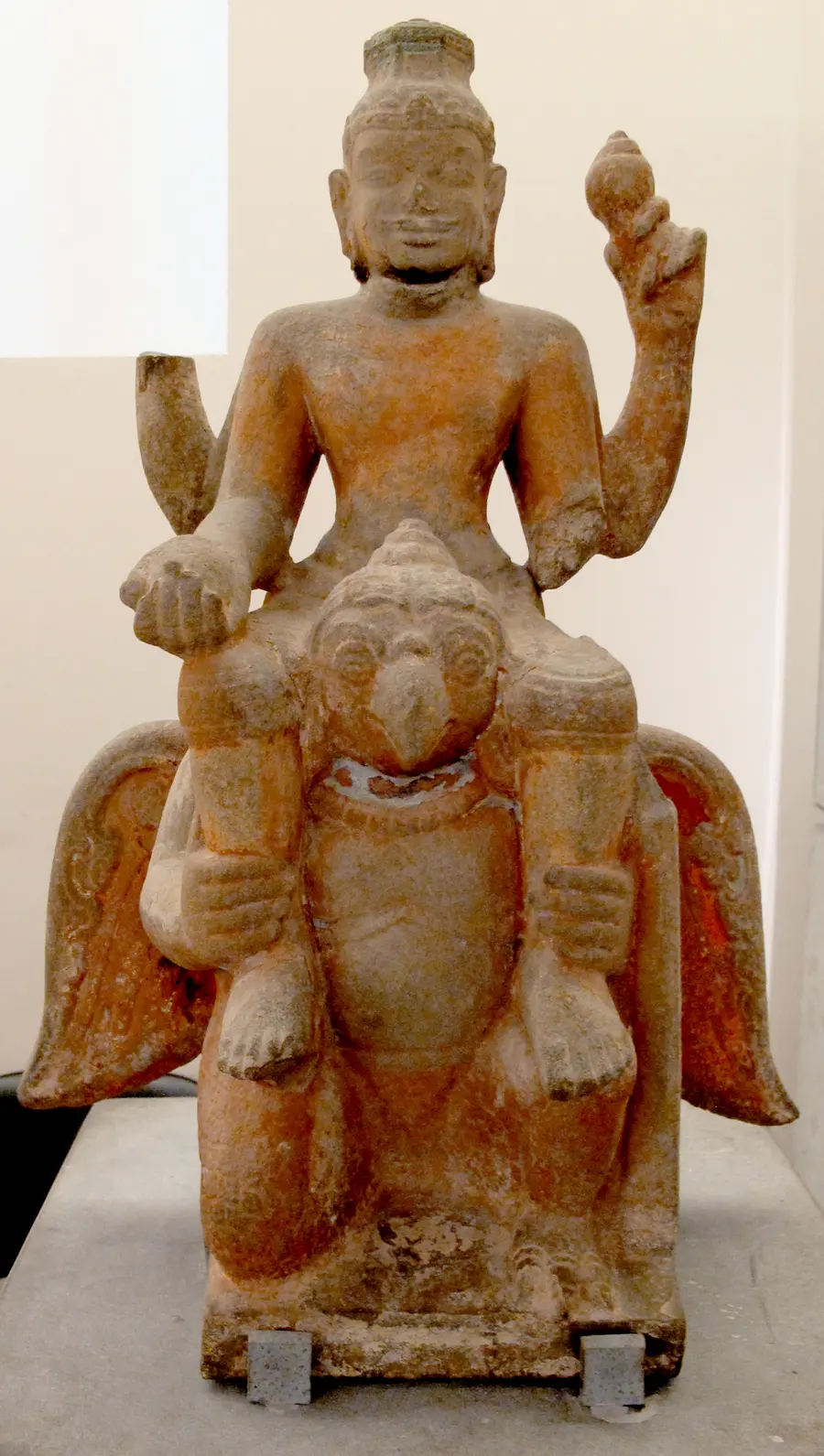 Cham stone statue of the god Vishnu seated on the back of the bird Garuda, wings spread on both sides.