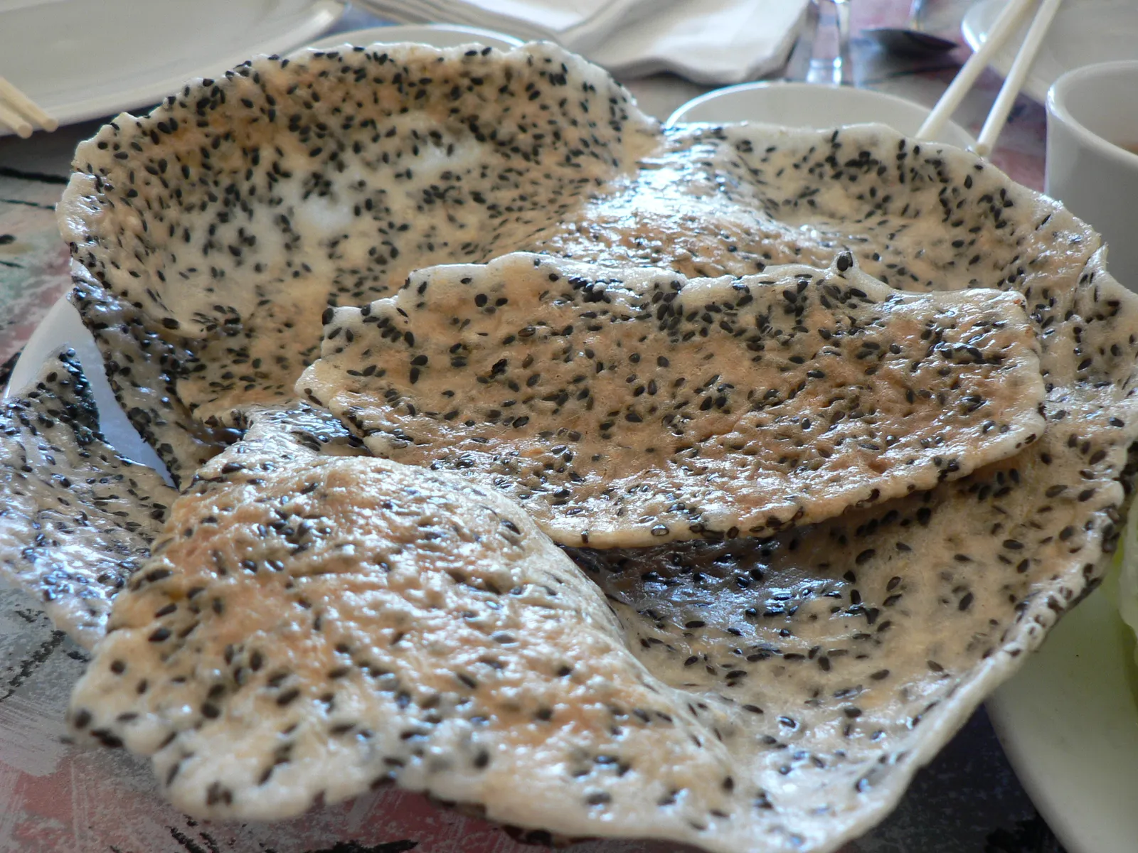 A stack of grilled rice crackers dotted with black sesame seeds on a plate.